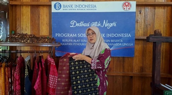 Ketua Rumah Tenun Lingga, Isnawati sedang menunjukkan dua helai kain hasil tenunannya. (uly)